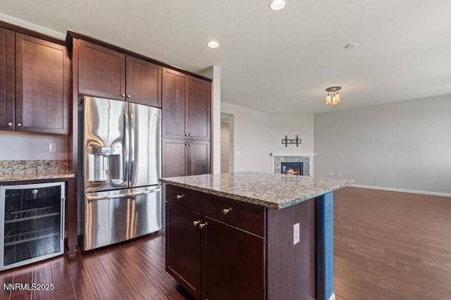 2720 Peavine Pines Ct, Reno, NV 89523 - kitchen featuring stainless steel refrigerator with ice dispenser, beverage cooler, dark wood-style floors, a warm lit fireplace, and a center island