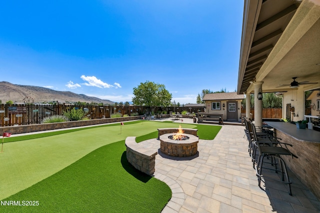 2885 Rio Vis, Minden, NV 89423 - view of patio / terrace with an outdoor fire pit, a putting area, a mountain view, and an outdoor structure