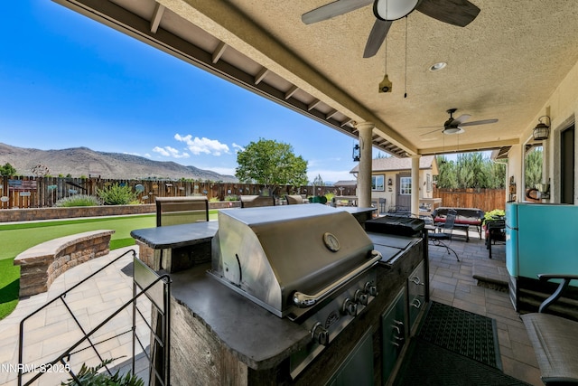 2885 Rio Vis, Minden, NV 89423 - fenced backyard featuring a ceiling fan, an outdoor kitchen, a patio, a mountain view, and outdoor lounge area