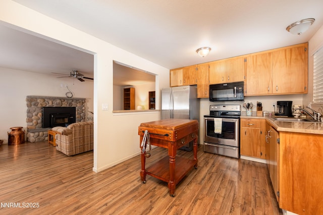 1399 Waterloo Ln, Gardnerville, NV 89410 - kitchen with stainless steel appliances, light countertops, light wood finished floors, a ceiling fan, and a stone fireplace