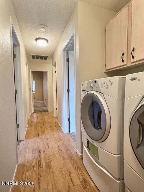 8425 Corrigan Way, Reno, NV 89506 - washroom featuring cabinet space, light wood-style flooring, washing machine and dryer, and a textured ceiling