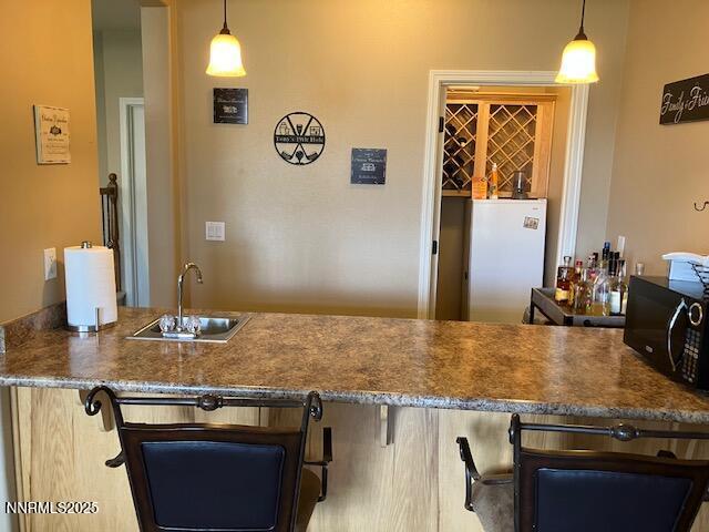 4073 Talladega Dr, Sparks, NV 89436 - kitchen with black microwave, a kitchen bar, hanging light fixtures, and freestanding refrigerator