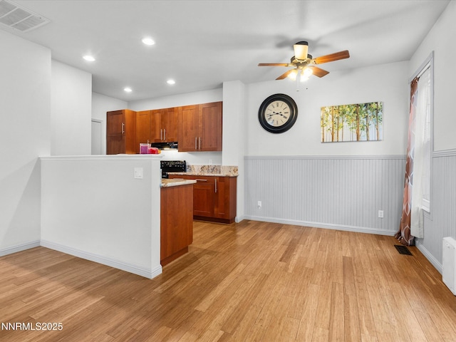 4325 Leeward Ln, Reno, NV 89502 - kitchen featuring light wood-style flooring, range, ceiling fan, brown cabinetry, and wainscoting