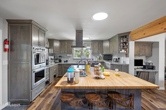 2450 Chukar Dr, Washoe Valley, NV 89704 - kitchen featuring stainless steel double oven, island exhaust hood, open shelves, dark wood-style floors, and butcher block counters