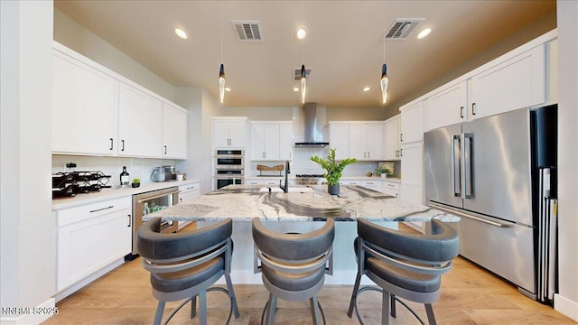 5517 Western Rider Trl, Reno, NV 89511 - kitchen with stainless steel appliances, wall chimney range hood, white cabinets, an island with sink, and a breakfast bar