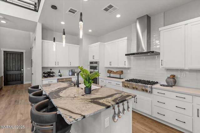 5517 Western Rider Trl, Reno, NV 89511 - kitchen with wall chimney range hood, stainless steel appliances, an island with sink, decorative backsplash, and a breakfast bar area