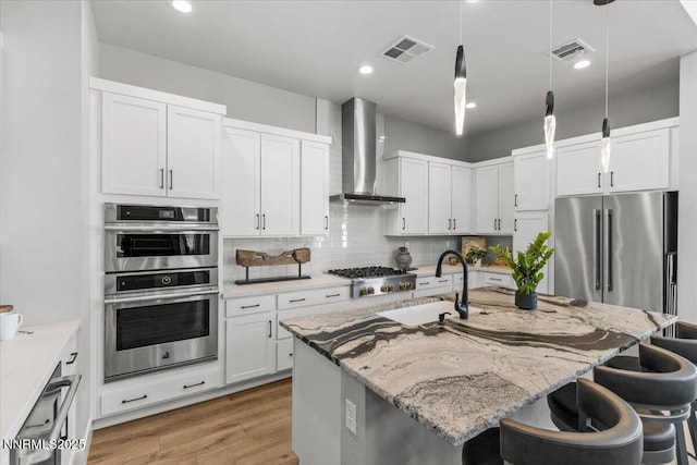 5517 Western Rider Trl, Reno, NV 89511 - kitchen featuring stainless steel appliances, wall chimney exhaust hood, a breakfast bar area, light stone countertops, and light wood-style flooring