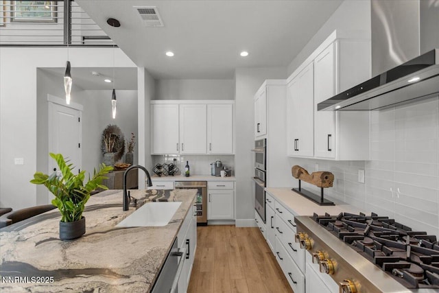 5517 Western Rider Trl, Reno, NV 89511 - kitchen featuring wall chimney range hood, stainless steel appliances, light stone countertops, white cabinets, and backsplash