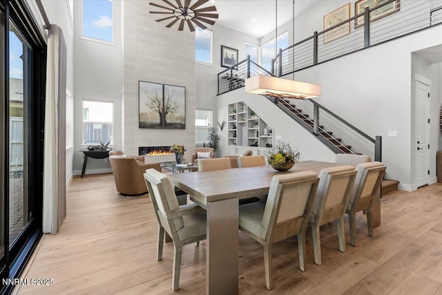 5517 Western Rider Trl, Reno, NV 89511 - dining space with a high ceiling, stairs, a fireplace, light wood-style flooring, and healthy amount of natural light