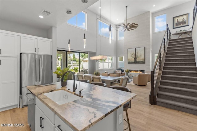 5517 Western Rider Trl, Reno, NV 89511 - kitchen with stainless steel appliances, light wood finished floors, a fireplace, white cabinets, and a high ceiling