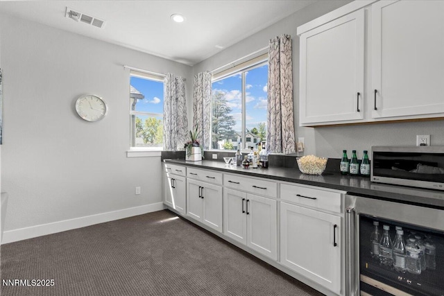 5517 Western Rider Trl, Reno, NV 89511 - kitchen featuring beverage cooler, stainless steel microwave, dark countertops, white cabinets, and recessed lighting