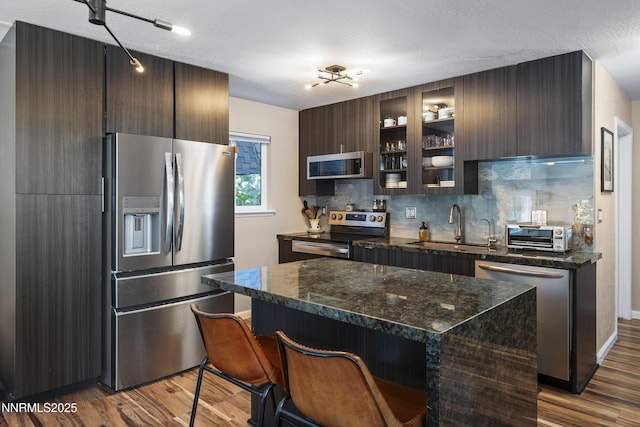 978 Glenrock Dr Unit 36, Incline Village, NV 89451 - kitchen featuring appliances with stainless steel finishes, wood finished floors, decorative backsplash, dark brown cabinetry, and a breakfast bar