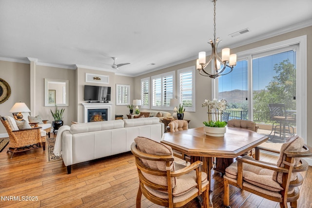 3579 Long Dr, Minden, NV 89423 - dining area with a chandelier, crown molding, light wood-style flooring, a glass covered fireplace, and a ceiling fan