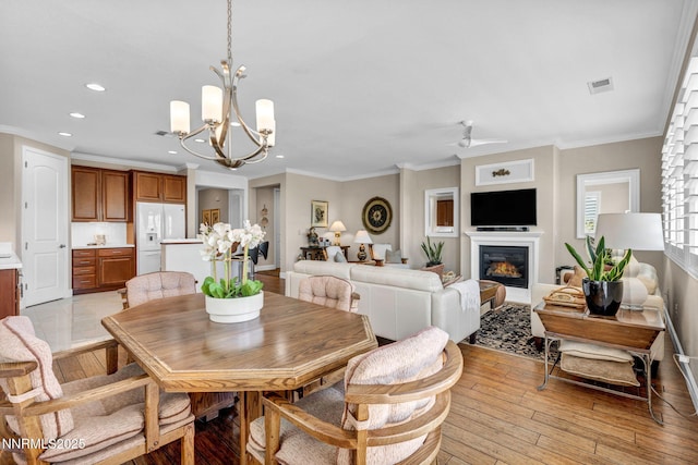 3579 Long Dr, Minden, NV 89423 - dining area with a chandelier, recessed lighting, a glass covered fireplace, ornamental molding, and light wood-style floors