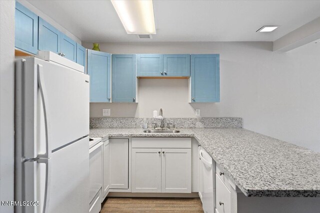 2555 Clear Acre Ln Apt 13, Reno, NV 89512 - kitchen featuring white appliances, blue cabinetry, a peninsula, and light wood-style floors
