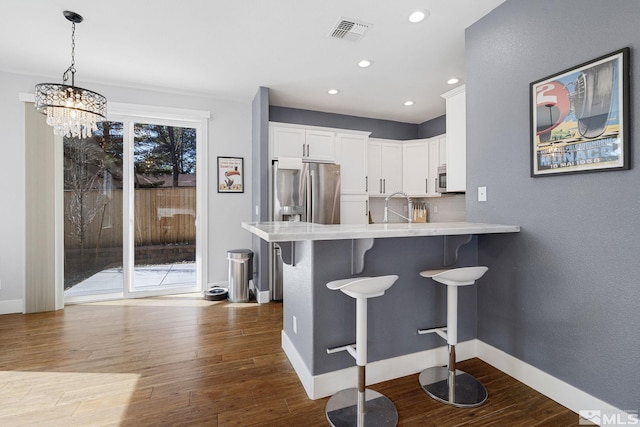 1585 Foster Dr, Reno, NV 89509 - kitchen featuring a breakfast bar area, light countertops, dark wood-style floors, white cabinetry, and a chandelier
