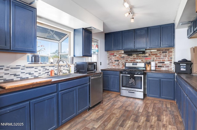 3480 York Ln, Fallon, NV 89406 - kitchen featuring appliances with stainless steel finishes, blue cabinets, backsplash, dark wood-type flooring, and under cabinet range hood