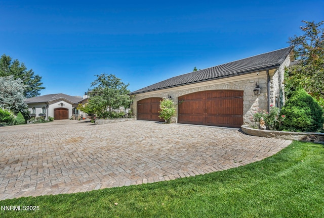 3820 Frost Ln, Reno, NV 89511 - view of side of home with decorative driveway, stone siding, an attached garage, and a tile roof