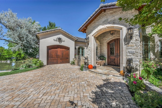 3820 Frost Ln, Reno, NV 89511 - view of exterior entry with stone siding, an attached garage, decorative driveway, a tiled roof, and stucco siding