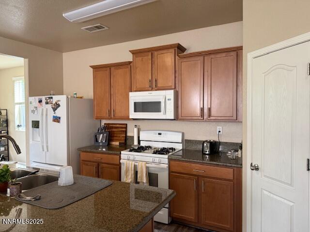 1108 Tuscan Ct, Minden, NV 89423 - kitchen with white appliances, dark countertops, and brown cabinetry