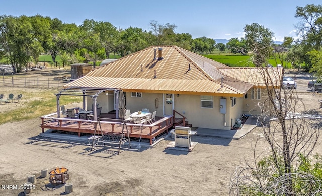 4525 Schurz Hwy, Fallon, NV 89406 - rear view of property featuring a wooden deck, a metal roof, stucco siding, and view of scattered trees