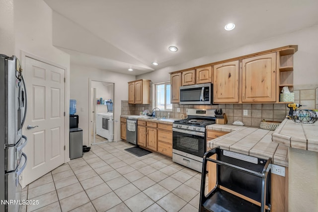 8030 Verde Ct, Winnemucca, NV 89445 - kitchen with stainless steel appliances, decorative backsplash, washer / clothes dryer, light tile patterned flooring, and tile countertops