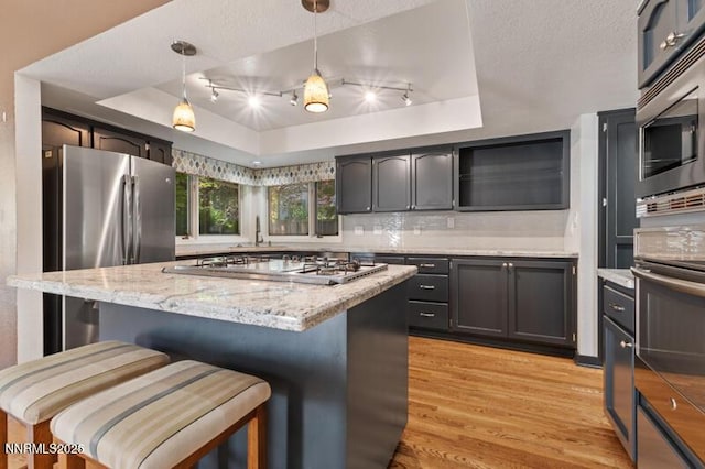 2126 Thomas Jefferson Dr, Reno, NV 89509 - kitchen featuring appliances with stainless steel finishes, light wood-style floors, a raised ceiling, a breakfast bar, and tasteful backsplash