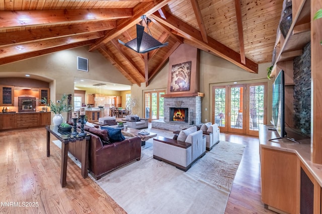 48 Rose Creek Ln, Reno, NV 89511 - living room featuring high vaulted ceiling, a wood ceiling with exposed beams, light wood finished floors, a stone fireplace, and french doors