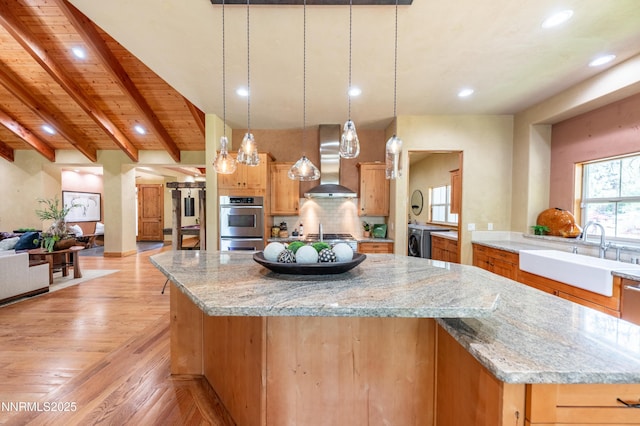 48 Rose Creek Ln, Reno, NV 89511 - kitchen featuring wall chimney range hood, washer / clothes dryer, backsplash, a spacious island, and recessed lighting