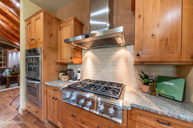 48 Rose Creek Ln, Reno, NV 89511 - kitchen featuring wall chimney range hood, appliances with stainless steel finishes, wood finished floors, light stone counters, and decorative backsplash