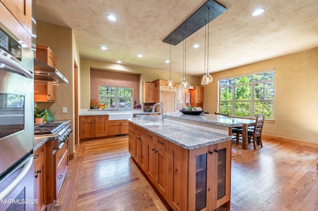 48 Rose Creek Ln, Reno, NV 89511 - kitchen featuring light wood-type flooring, brown cabinets, appliances with stainless steel finishes, a kitchen island with sink, and recessed lighting