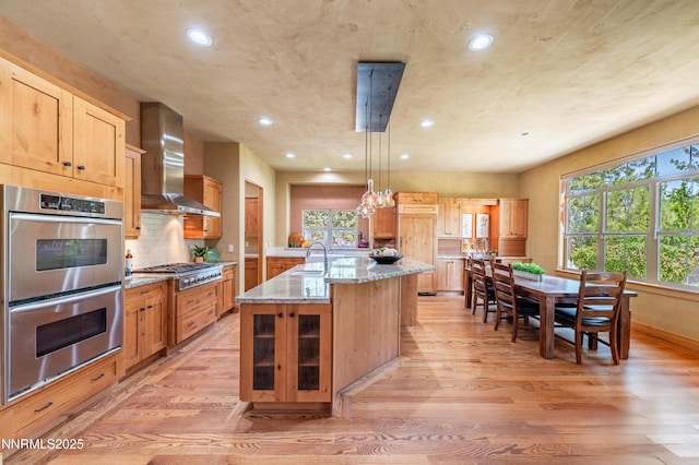 48 Rose Creek Ln, Reno, NV 89511 - kitchen with appliances with stainless steel finishes, wall chimney exhaust hood, light wood-style flooring, recessed lighting, and light stone countertops