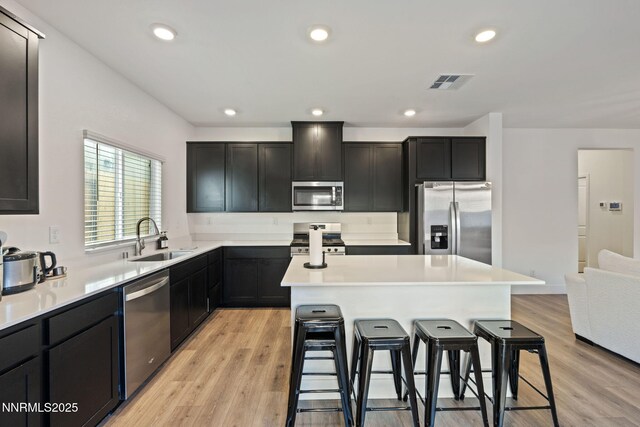 1413 Solitude Trl, Reno, NV 89523 - kitchen with stainless steel appliances, a breakfast bar, a center island, light wood-style flooring, and recessed lighting