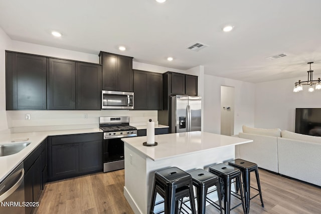 1413 Solitude Trl, Reno, NV 89523 - kitchen with stainless steel appliances, a kitchen breakfast bar, open floor plan, light wood-style flooring, and recessed lighting