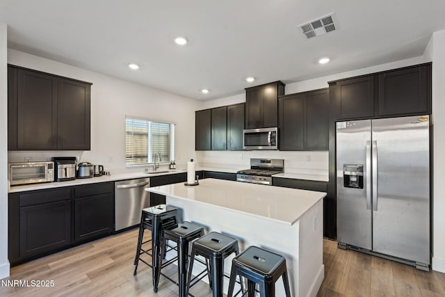 1413 Solitude Trl, Reno, NV 89523 - kitchen with stainless steel appliances, a kitchen breakfast bar, light wood-style flooring, recessed lighting, and light countertops