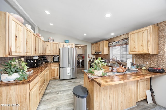 6297 Cox Rd, Fallon, NV 89406 - kitchen with freestanding refrigerator, light brown cabinetry, separate washer and dryer, vaulted ceiling, and recessed lighting