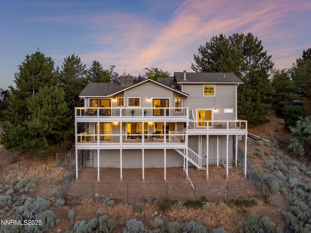 3575 Cashill Blvd, Reno, NV 89509 - back of property at dusk with a fenced backyard, a patio, a chimney, stairs, and a deck