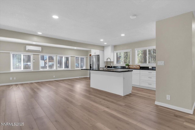 1094 Johnson Blvd, South Lake Tahoe, CA 96150 - kitchen with stainless steel fridge with ice dispenser, a wall mounted air conditioner, white cabinets, light wood-type flooring, and dark countertops