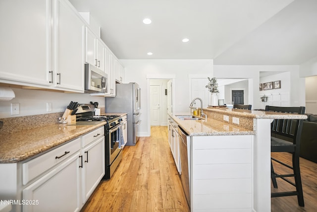 3287 Hackamore Way, Winnemucca, NV 89445 - kitchen featuring appliances with stainless steel finishes, a breakfast bar area, white cabinetry, light wood-type flooring, and a center island with sink