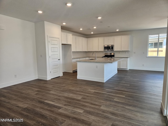 1205 Spur Way, Gardnerville, NV 89410 - kitchen with stainless steel appliances, white cabinets, light stone counters, a center island with sink, and dark wood-style flooring
