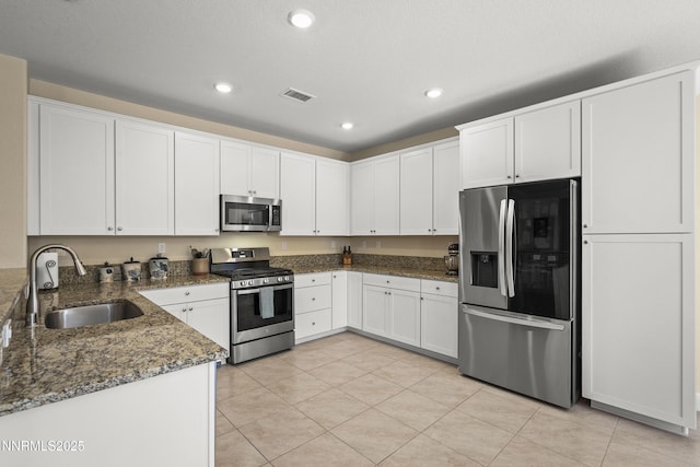 7106 Owl Vw Dr, Sparks, NV 89436 - kitchen with appliances with stainless steel finishes, recessed lighting, dark stone countertops, light tile patterned flooring, and white cabinetry
