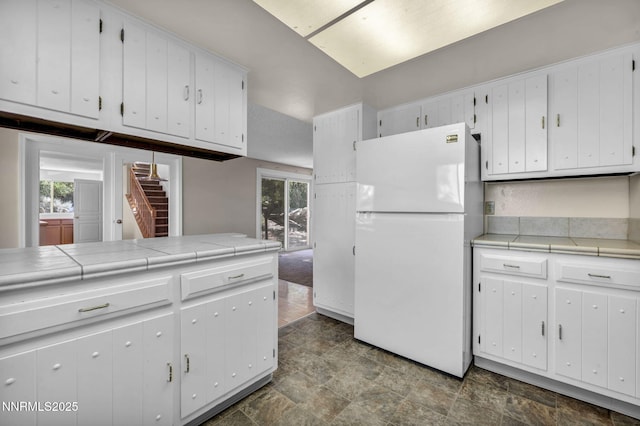 1425 Julie Ct, Reno, NV 89509 - kitchen with freestanding refrigerator, stone finish floors, white cabinetry, and tile countertops