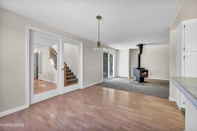 1425 Julie Ct, Reno, NV 89509 - unfurnished living room with a textured ceiling, light wood-type flooring, a wood stove, and stairs
