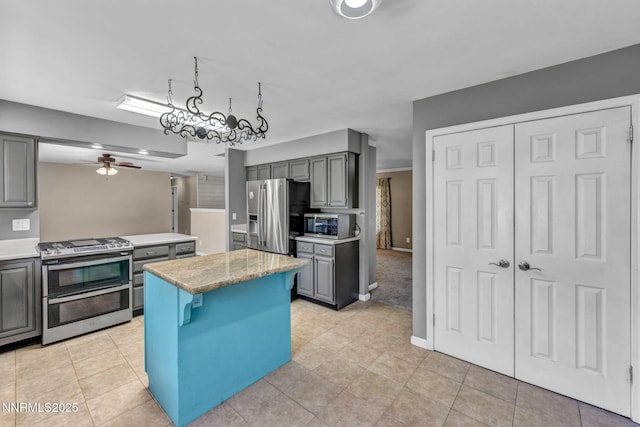 4210 Magnolia Rd, Fallon, NV 89406 - kitchen with appliances with stainless steel finishes, gray cabinetry, a kitchen island, a ceiling fan, and light tile patterned floors