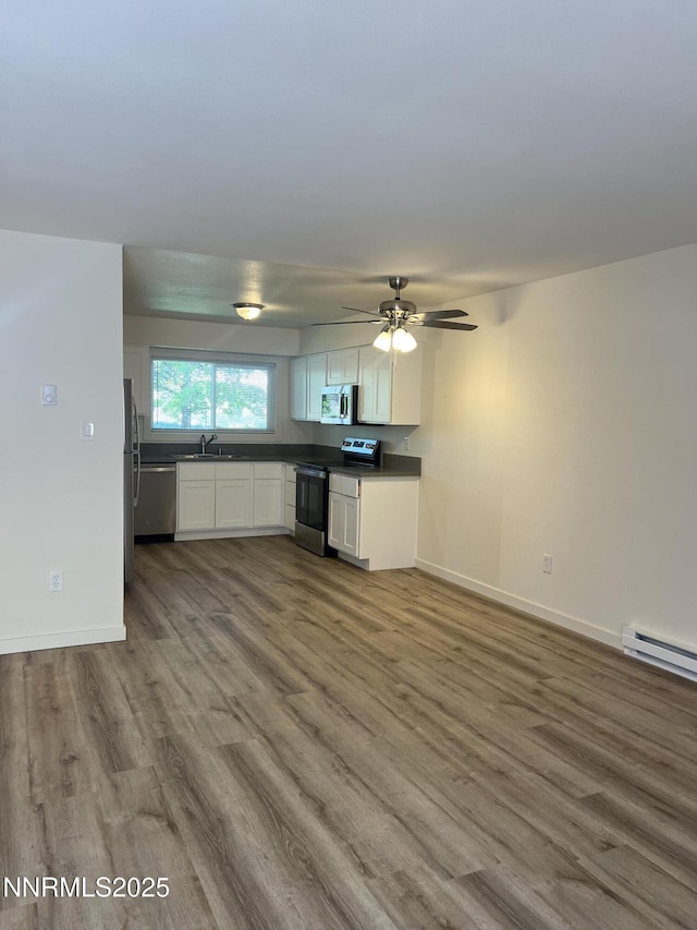 385 Smithridge Park Unit 3Ut4Lt, Reno, NV 89502 - kitchen with appliances with stainless steel finishes, dark countertops, wood finished floors, a baseboard heating unit, and white cabinets