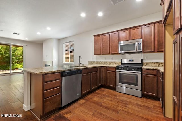 1460 Waterloo Dr, Reno, NV 89509 - kitchen with stainless steel appliances, a peninsula, dark wood-style floors, recessed lighting, and light stone countertops
