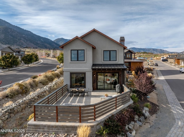 2912 Portrush Dr, Genoa, NV 89411 - back of house featuring a chimney, a mountain view, stucco siding, and a standing seam roof