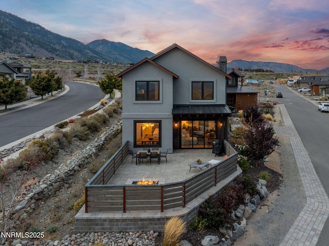 2912 Portrush Dr, Genoa, NV 89411 - back of house featuring a fire pit, a mountain view, stucco siding, a chimney, and a standing seam roof