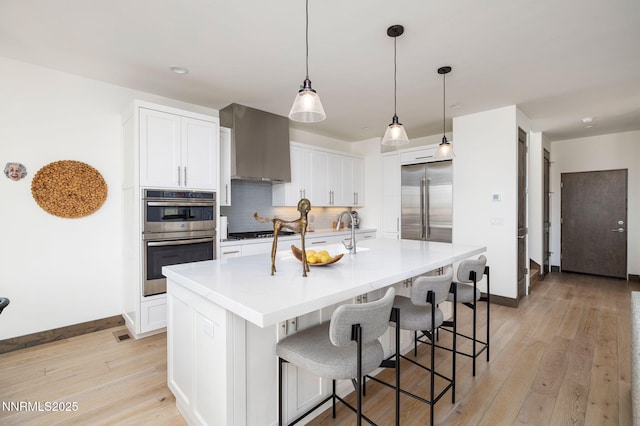 2912 Portrush Dr, Genoa, NV 89411 - kitchen featuring appliances with stainless steel finishes, wall chimney range hood, light wood-type flooring, tasteful backsplash, and a breakfast bar