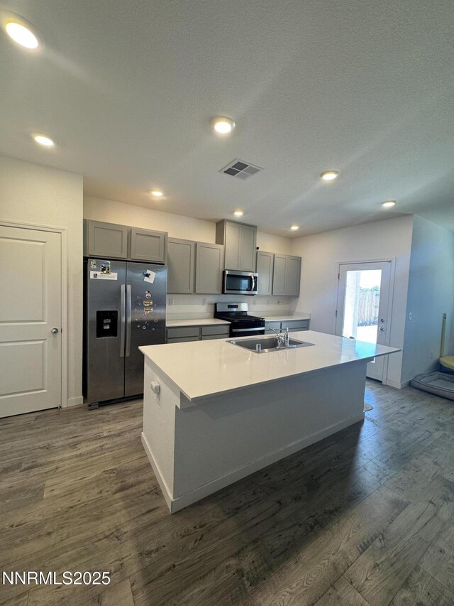 427 Agate Ln, Fallon, NV 89406 - kitchen featuring appliances with stainless steel finishes, gray cabinets, light countertops, a center island with sink, and dark wood-style flooring